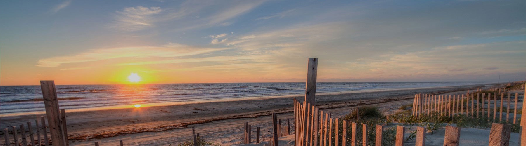 The sun setting over an ocean and sandy beach