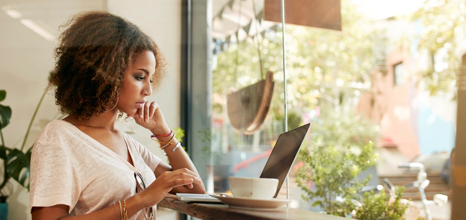 A woman in a coffee shop looking at a laptop