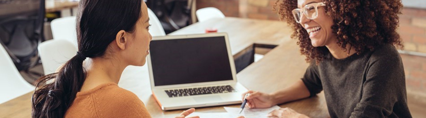 Two women smiling while discussing paperwork